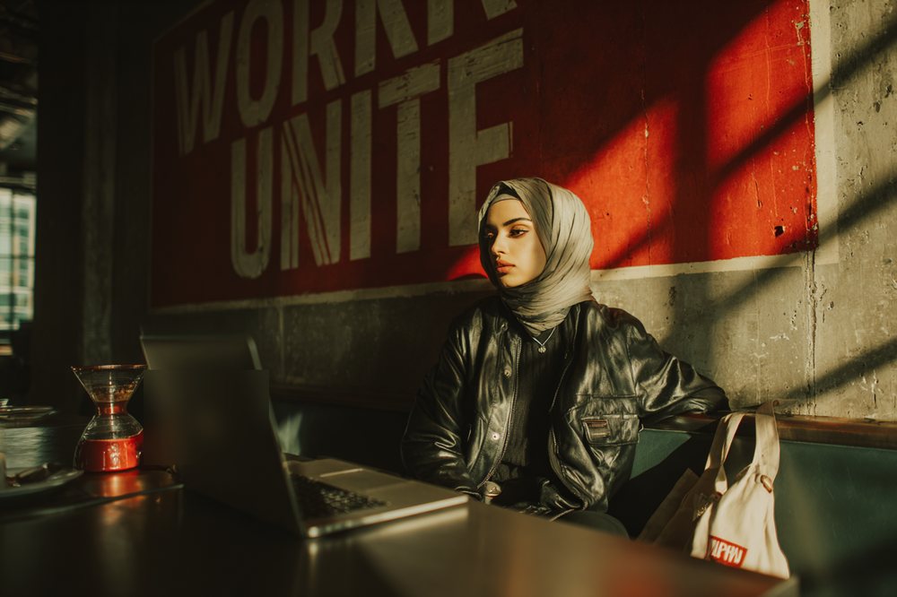 A patron working on a laptop beneath a WORKERS UNITE mural at Cafe Socialist