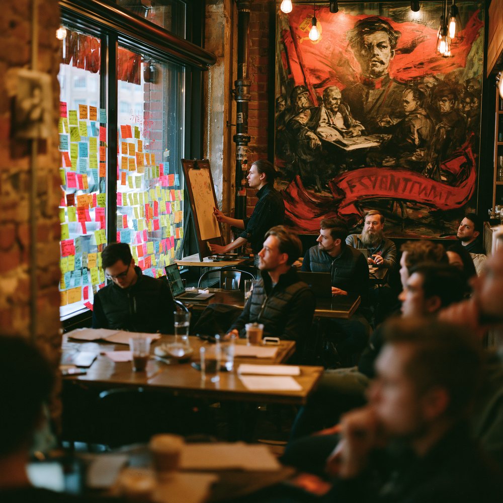 A corporate team in matching vests holding an offsite meeting with sticky notes on the cafe window