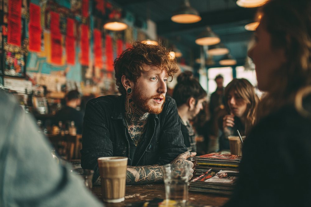 A patron in conversation over coffee at a communal table at Cafe Socialist