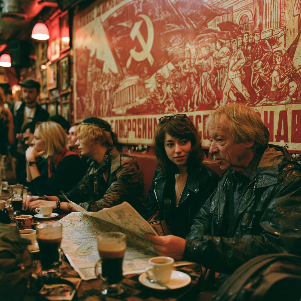 A cheerful tourist couple studying a paper map at a cafe table among stylish patrons